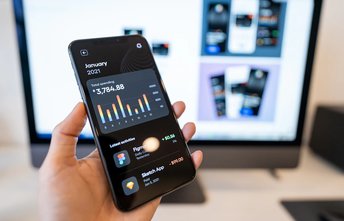 Hand holding a phone that shows a finance app dashboard